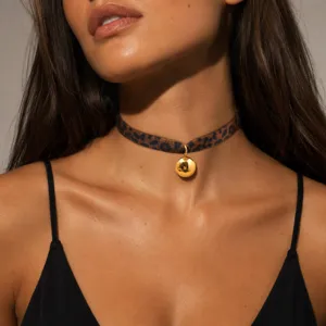 Primer plano detallado de un collar gargantilla de moda con estampado de leopardo y colgante dorado.
