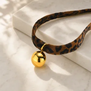 Primer plano de gargantilla de terciopelo con estampado de leopardo y colgante dorado.