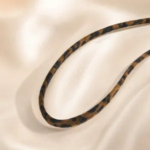 Detalle de primer plano de un collar de cordón de tela con leopardo sobre fondo de seda.