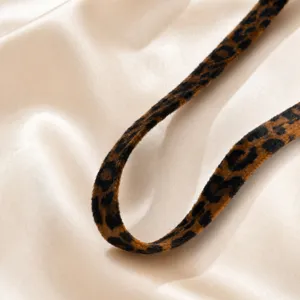 Vista detallada de una elegante correa de gargantilla con estampado de leopardo en fondo sedoso.
