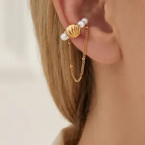 Vista di dettaglio di un cuff auricolare dorato in acciaio con perle e ciondolo a conchiglia.