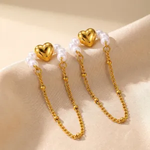 Primo piano dettaglio del polsino per orecchio con catena cuore perle in acciaio oro.