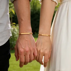 Detalle de pulsera de acero dorado para parejas, diseño curvo pulido para uso diario.
