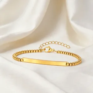 Detalle de pulsera de acero inoxidable dorada con placa curva lisa y elegante cadena de caja.