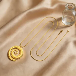 Primo piano dettagliato di un elegante ciondolo a conchiglia a spirale dorata su tessuto satin.
