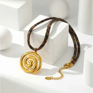 Vista dettagliata del ciondolo a spirale dorato e della collana con cordino leopardato.