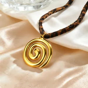 Collana con ciondolo a spirale dorato e cordino leopardato chic su sfondo di seta.