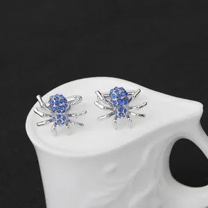 Vue détaillée de boutons de manchette élégants en forme d'araignée avec des strass bleus.