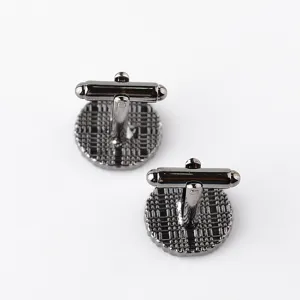 Close-up detail of stylish round gunmetal cufflinks with classic check pattern for men shirts.