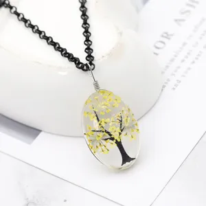 Primo piano dettagliato della collana con ciondolo ad albero di fiori secchi in resina.