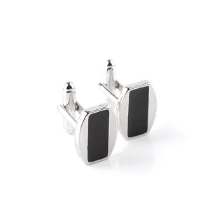 Gros plan de boutons de manchette argentés classiques avec un insert rectangulaire noir.