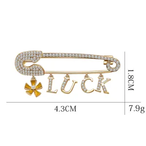 Broche épingle de sûreté dorée LUCK tendance avec strass brillants et fleur en émail.