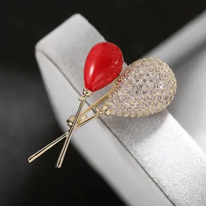 Close-up detail of the creative double balloon brooch featuring red enamel and sparkling zircon.