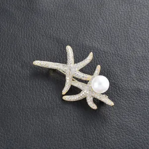 Close-up of exquisite gold starfish pearl brooch with sparkling zirconia stones and pearl.