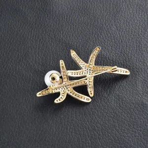 Detail shot of the gold-toned double starfish and pearl brooch showing fine rhinestone inlay and pin.