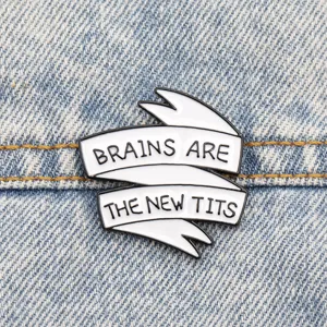 Nahaufnahme eines schwarz-weißen Emaille-Pins mit witzigem Slogan auf Jeansstoff.