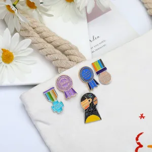 Close-up detail of creative enamel pins featuring cute space and ribbon medal designs.