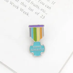 Close-up of colorful enamel medal pin with inspirational English text for clothing and bags.