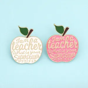 Close-up view of teacher apple enamel brooch pin details, gold rim metal badge accessory.