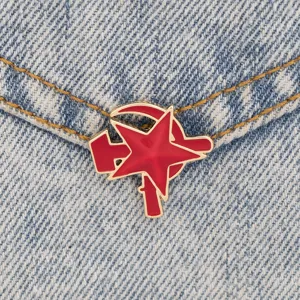 Gros plan d'une broche émaillée étoile rouge marteau et faucille soviétique sur tissu en denim.