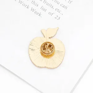 Back detail of gold apple brooch pin, showing secure clasp and durable metal craft construction.