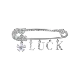 Gros plan d'une broche épingle de sûreté en cristal étincelant avec lettres LUCK et fleur.