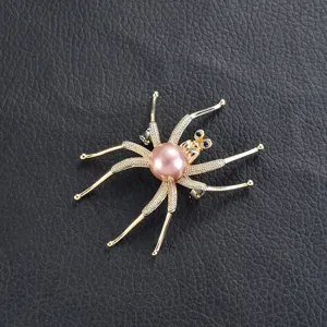 Nahaufnahme der Vintage-Spinnenbrosche mit rosa Perle und funkelnden Strasssteinen.