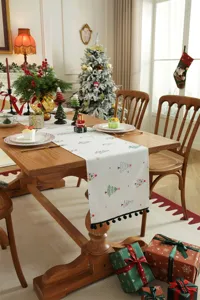 Camino da tavola natalizio con stampa di alberi e frange per decorazioni festive.
