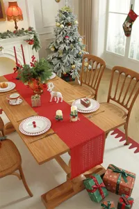 Roter gestrickter Weihnachtstischläufer mit festlicher Esstischdekoration im gemütlichen Raum.