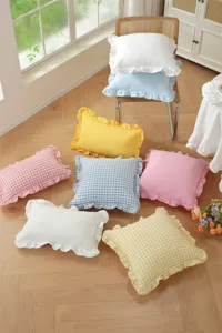 Detailed shot of French pastoral cotton ruffled pillows and checkered cushion covers in indoor decor.