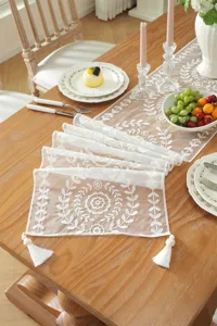 White lace embroidered floral table runner with tassels for wedding and home decoration detail.