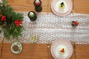 White mesh Christmas table runner with silver foil tree print for holiday dining decor detail.
