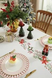 Detailweergave van kerst geborduurde tafelkleed met feestelijk poinsettia ranken patroon.