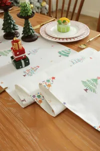 Dettaglio in primo piano del runner da tavola con stampa natalizia in ambiente accogliente.