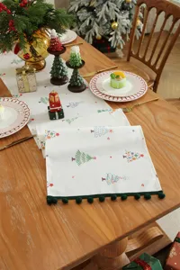 Camino da tavola natalizio con frange a ponpon, decorazione festiva per la tavola da pranzo.
