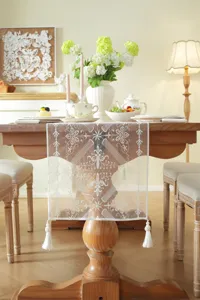 Close-up detail of white lace embroidered table runner showcasing intricate floral geometric patterns.