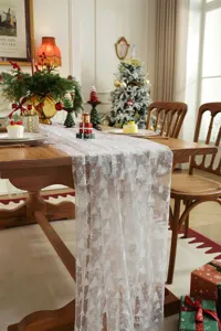 White lace table runner with Christmas tree and snowflake prints for holiday dining decor.