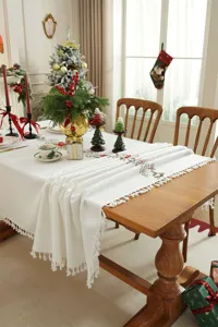 Mooi kerstgeborduurd tafelkleed met delicate feestelijke motieven en elegante franjes.