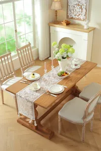 Elegant white lace floral table runner with tassels, perfect for wedding and dining decor.