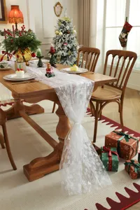 White mesh lace Christmas table runner with silver stamped trees for holiday dining decor detail.