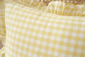 Close-up detail of yellow and white gingham plaid pillow cover with elegant ruffle edge.