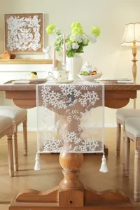 White lace table runner with floral embroidery and tassels for dining table decor.