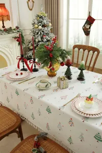 Detalle mantel estampado árbol de navidad, decoración mesa festiva con borlas y patrones.