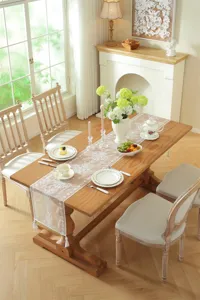 Detailed view of white lace table runner featuring delicate floral embroidery and elegant tassels.