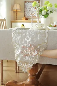 White and gold lace table runner with star and moon embroidery, elegant dining cover.