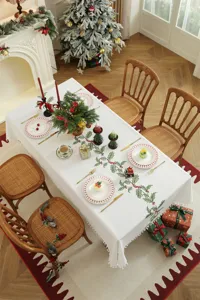 Kersttafelkleed met geborduurd hulstmotief en stijlvolle kwastjesrand voor feestdagen.