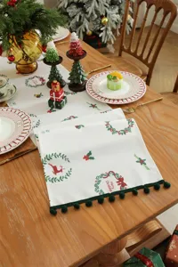 Corsia da tavola natalizia con stampa di ghirlanda festiva e frangia verde di pon-pon per feste.