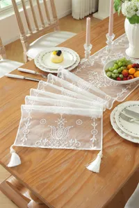 Elegant white lace table runner with floral embroidery and delicate tassels for wedding table decor.