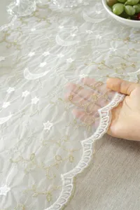Close-up detail of white and gold star moon lace embroidery fabric showing sheer texture.