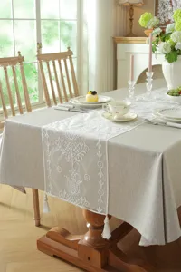 Detailed view of the white lace embroidered floral geometric table runner with elegant tassels.